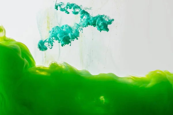 Close up view of mixing of green and bright turquoise paints splashes in water isolated on gray — Stock Photo