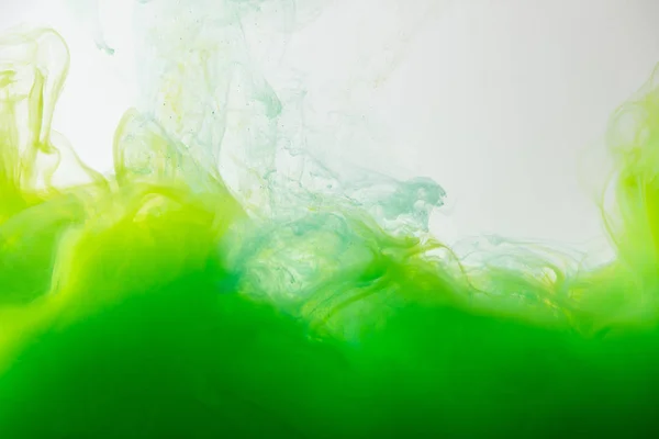 Close up view of mixing of green and yellow paints splashes in water isolated on gray — Stock Photo