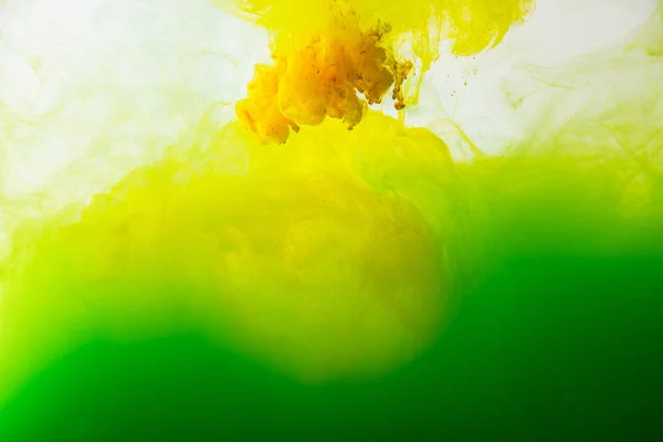 Close up view of mixing of green and yellow paints splashes in water isolated on gray — Stock Photo