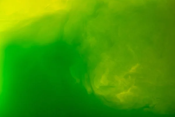 Full frame image of mixing of green and yellow paints splashes in water isolated on gray — Stock Photo