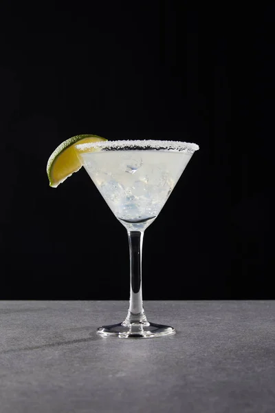 Close up view of tasty margarita cocktail with lime and ice on tabletop on black — Stock Photo