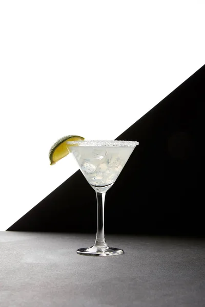 Close up view of tasty margarita cocktail with lime and ice on tabletop on black and white backdrop — Stock Photo