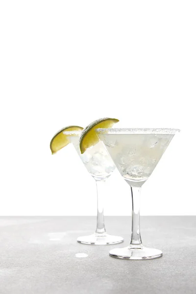 Vista de perto de coquetéis de margarita de álcool com limão na superfície cinza no branco — Fotografia de Stock