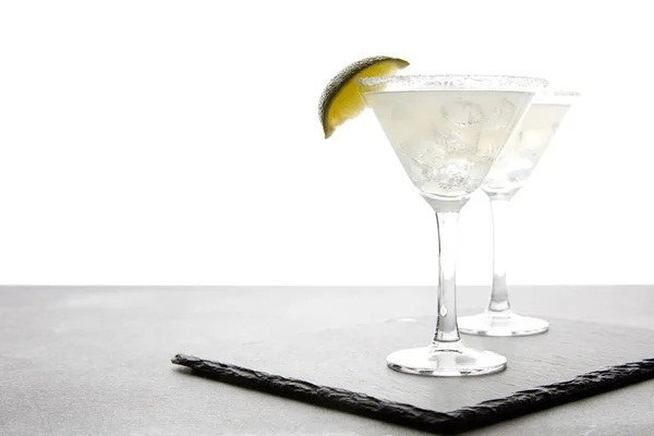 Close up view of alcohol cocktails with lime on grey surface on white — Stock Photo