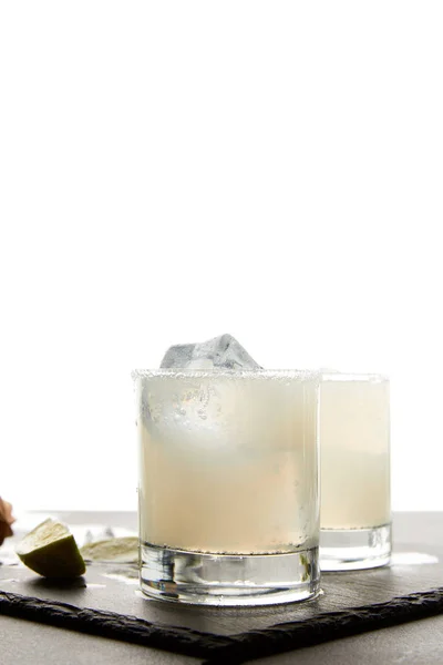 Vue rapprochée de cocktails rafraîchissants au caïpirinha avec de la chaux et de la glace sur table sur fond blanc — Photo de stock