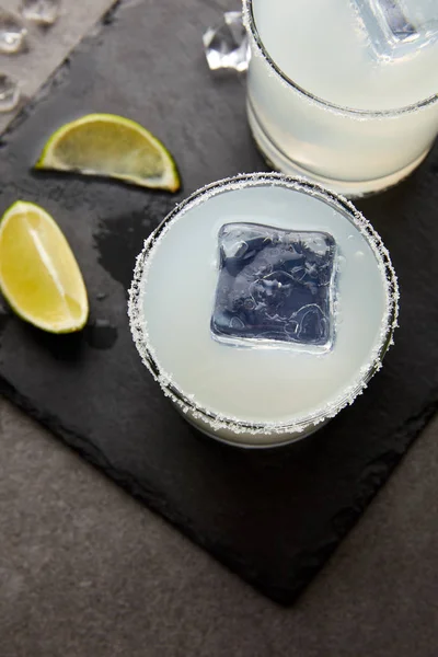 Vista de cerca de refrescantes cócteles de caipirinha de alcohol agrio con trozos de hielo y lima en la mesa - foto de stock