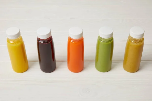 Fresh organic smoothies in bottles standing in row on white — Stock Photo