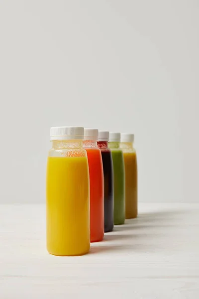 Fresh detox smoothies in bottles standing in row on white — Stock Photo