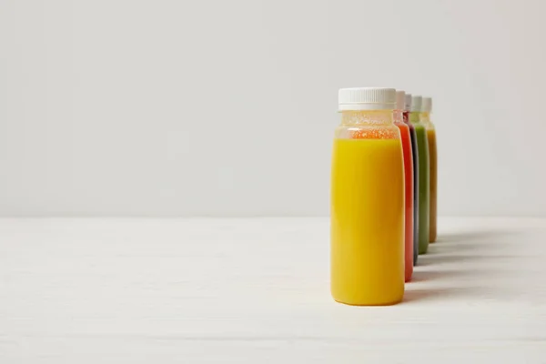 Colorful detox smoothies in bottles standing in row on white — Stock Photo