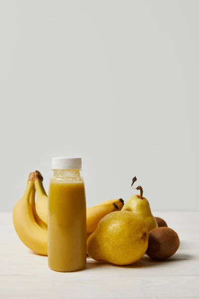 Smoothie amarelo desintoxicação em garrafa com bananas, kiwis e peras sobre fundo branco — Fotografia de Stock