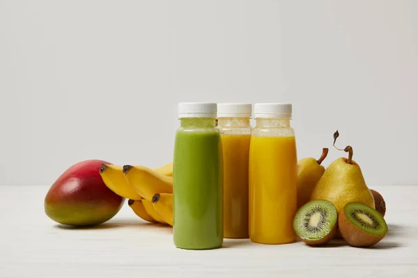 Organic fruits and fresh smoothies in bottles on white background — Stock Photo