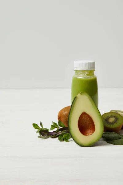 Batido de desintoxicación fresco con aguacate verde, kiwi y menta en la superficie de madera blanca - foto de stock