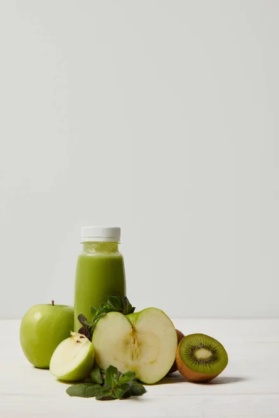 Bottle of detox smoothie with green apples, kiwi and mint and on white wooden surface — Stock Photo