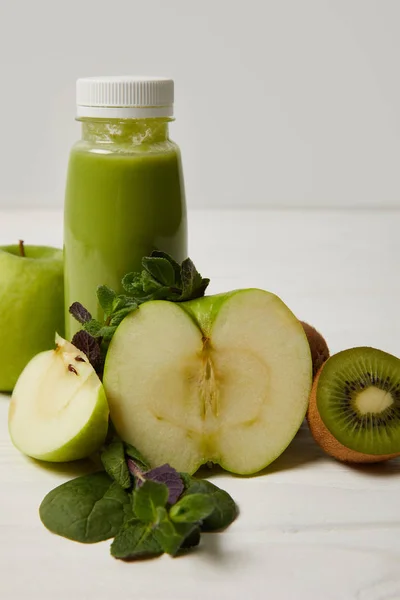 Flasche grüner Detox-Smoothie mit Äpfeln, Kiwi und Minze auf weißer Holzoberfläche — Stockfoto