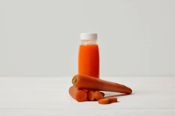 Bottiglia di frullato disintossicante con carote su superficie di legno bianca — Foto stock