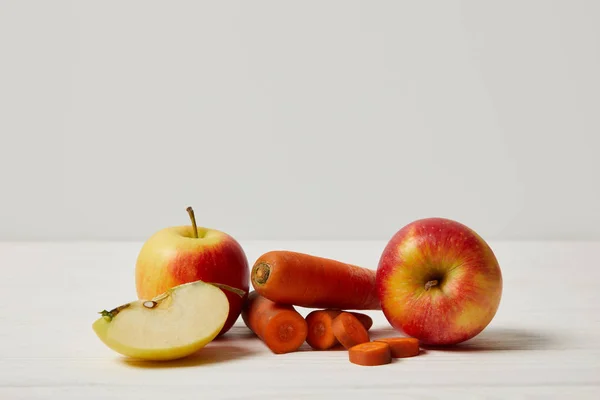 Zanahorias frescas y manzanas en la superficie de madera - foto de stock