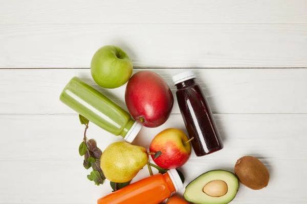 Draufsicht auf frisches Obst und Detox-Smoothies auf weißem Holzhintergrund — Stockfoto