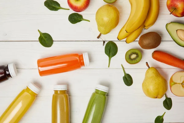 Vista dall'alto di frutta fresca e bottiglie con frullati su sfondo di legno — Foto stock