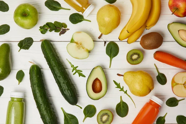 Flat lay com frutas frescas coloridas e legumes e garrafas com smoothies em fundo de madeira — Fotografia de Stock