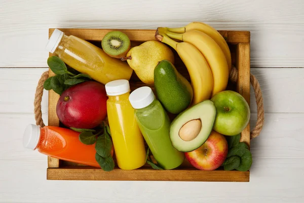 Vista superior de frutas e smoothies de desintoxicação em caixa de madeira — Fotografia de Stock