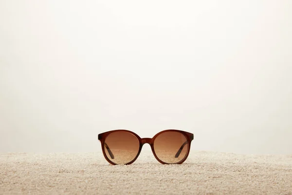 Vista de cerca de las gafas de sol sobre arena sobre fondo gris - foto de stock
