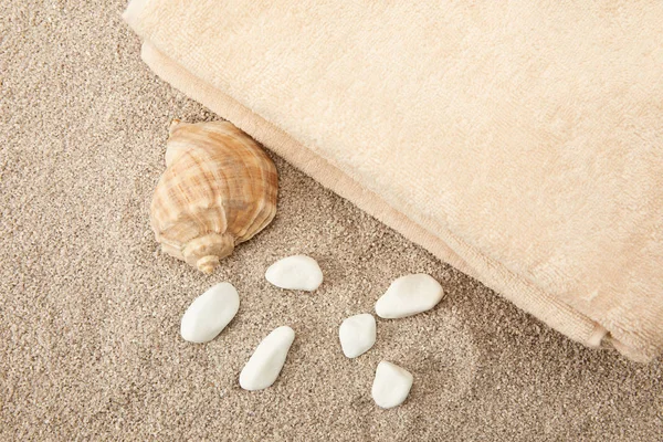 Top view of seashell, sea stones and towels on sand — Stock Photo