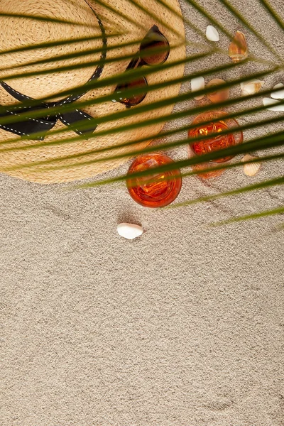 Top view of arranged straw hat, sunglasses, cocktails, seashells on sand and palm leaf — Stock Photo