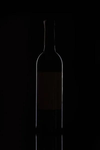 Vista de primer plano de la botella con vino tinto aislado sobre fondo negro - foto de stock