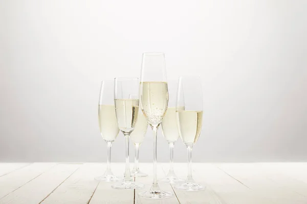 Vista de cerca de copas de champán en mesa de madera blanca - foto de stock