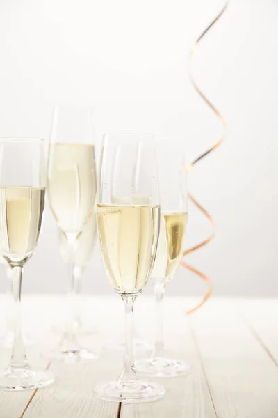Vista ravvicinata di bicchieri di champagne con nastro su tavolo di legno bianco, concetto di vacanza — Foto stock
