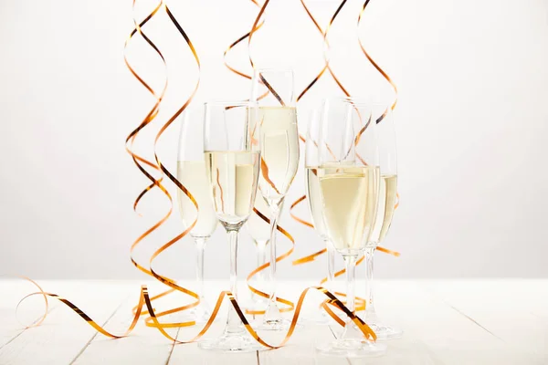 Champagne glasses with ribbons on white wooden table, holiday concept — Stock Photo