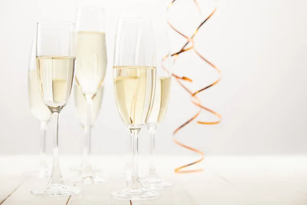 Close up view of champagne glasses with ribbons on white wooden table, holiday concept — Stock Photo