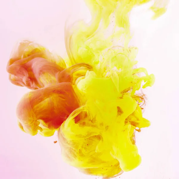 Fond artistique avec peinture jaune et rouge fluide sur rose — Photo de stock