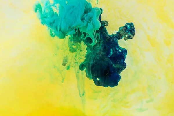 Background with green and turquoise paint flowing in yellow water — Stock Photo