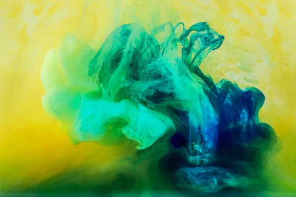 Fundo com tinta verde fluindo em água amarela — Fotografia de Stock