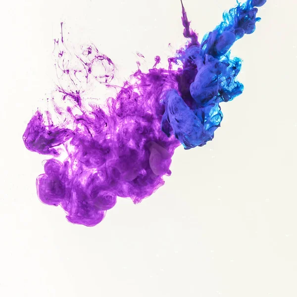 Smoky splashes of blue and purple paint in water, isolated on white — Stock Photo