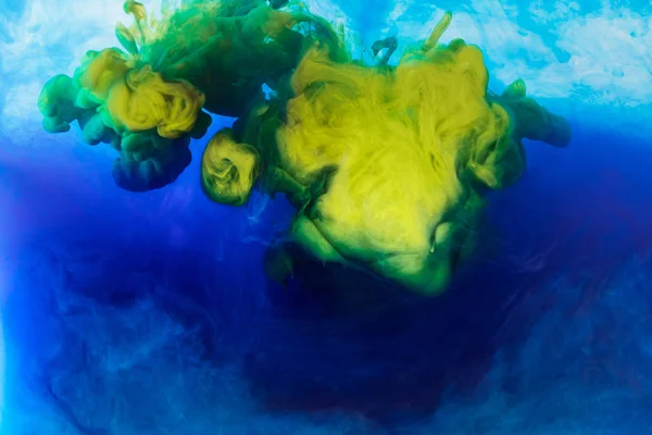 Abstract background with blue and yellow paint mixing in water — Stock Photo