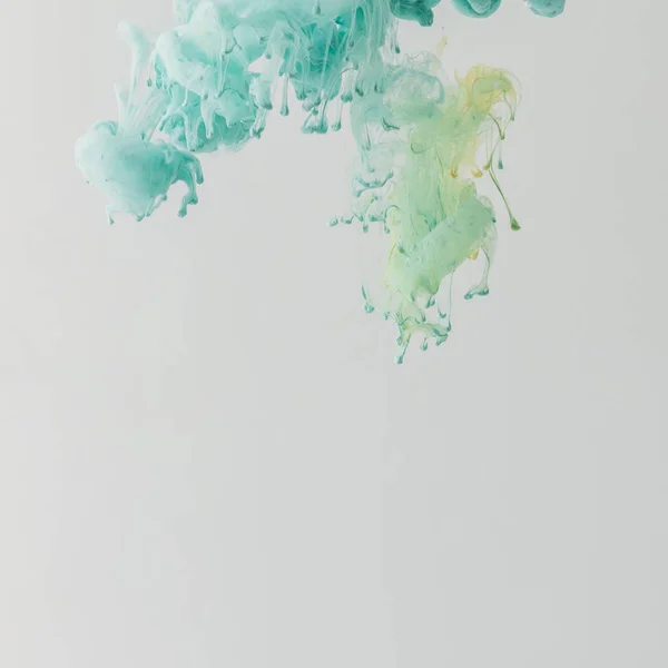 Pintura turquesa clara que fluye en agua con gotas, aislada en gris — Stock Photo
