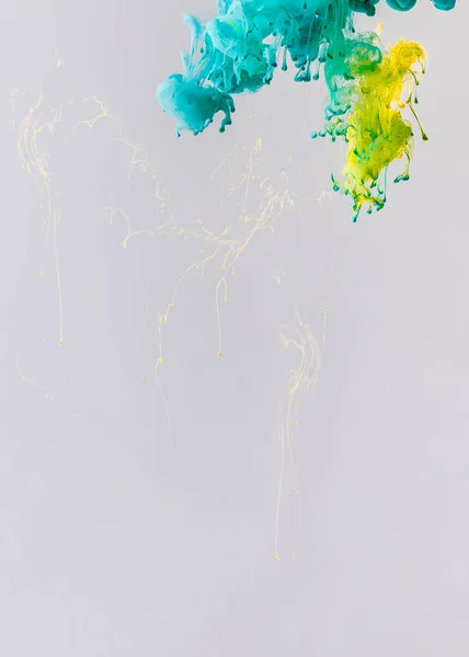 Background with turquoise and yellow paint flowing in water with drops, isolated on grey — Stock Photo