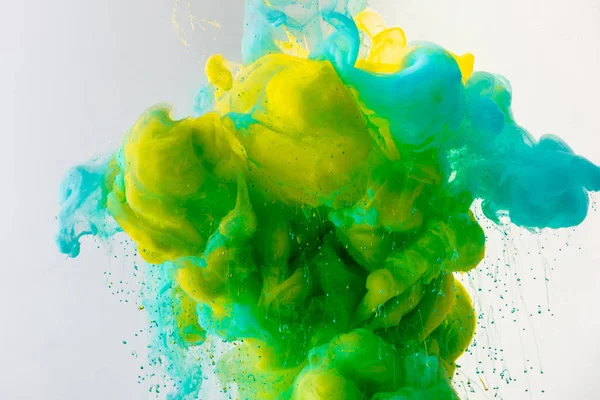 Fondo artístico con fluido turquesa, pintura amarilla y verde en agua, aislado en gris — Stock Photo