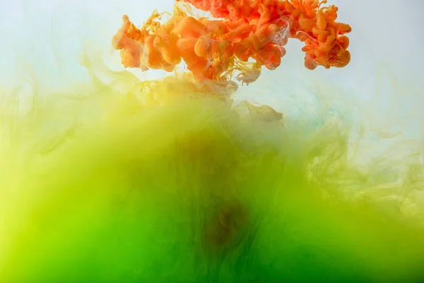 Акриловий фон зі змішуванням зеленої, жовтої та помаранчевої фарби у воді — стокове фото