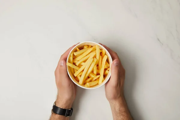 Cropped shot of man holding bowl of french fries on white — Stock Photo