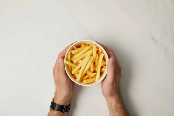 Tiro recortado de hombre sosteniendo tazón de papas fritas en blanco - foto de stock