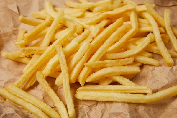 Primo piano di deliziose patatine fritte versate su carta spiegazzata — Foto stock