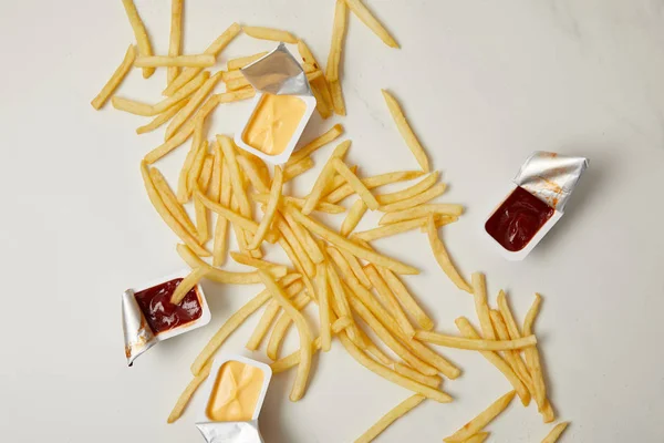 Vista superior de batatas fritas com recipientes de molhos em branco — Fotografia de Stock