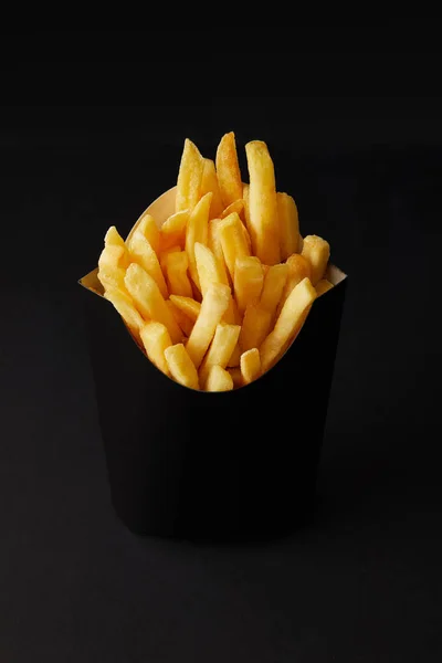 Primer plano de caja negra de sabrosas papas fritas aisladas en negro aisladas en negro - foto de stock