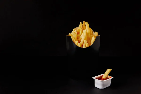 Коробка картоплі фрі з пластиковим контейнером кетчупу ізольовані на чорному — стокове фото