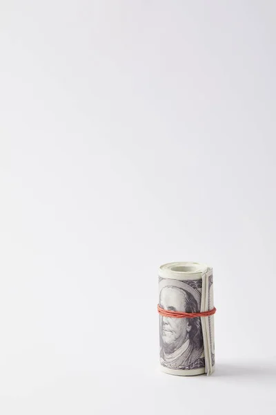 Roll of dollars tied with red rubber band on white — Stock Photo