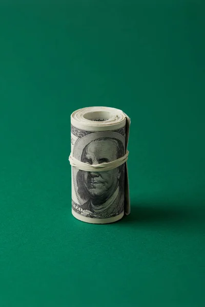 Rolo de dólares amarrado com faixa de borracha na superfície azul — Fotografia de Stock