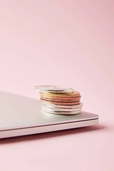 Close-up shot of bitcoins stacked on closed laptop on pink surface — Stock Photo